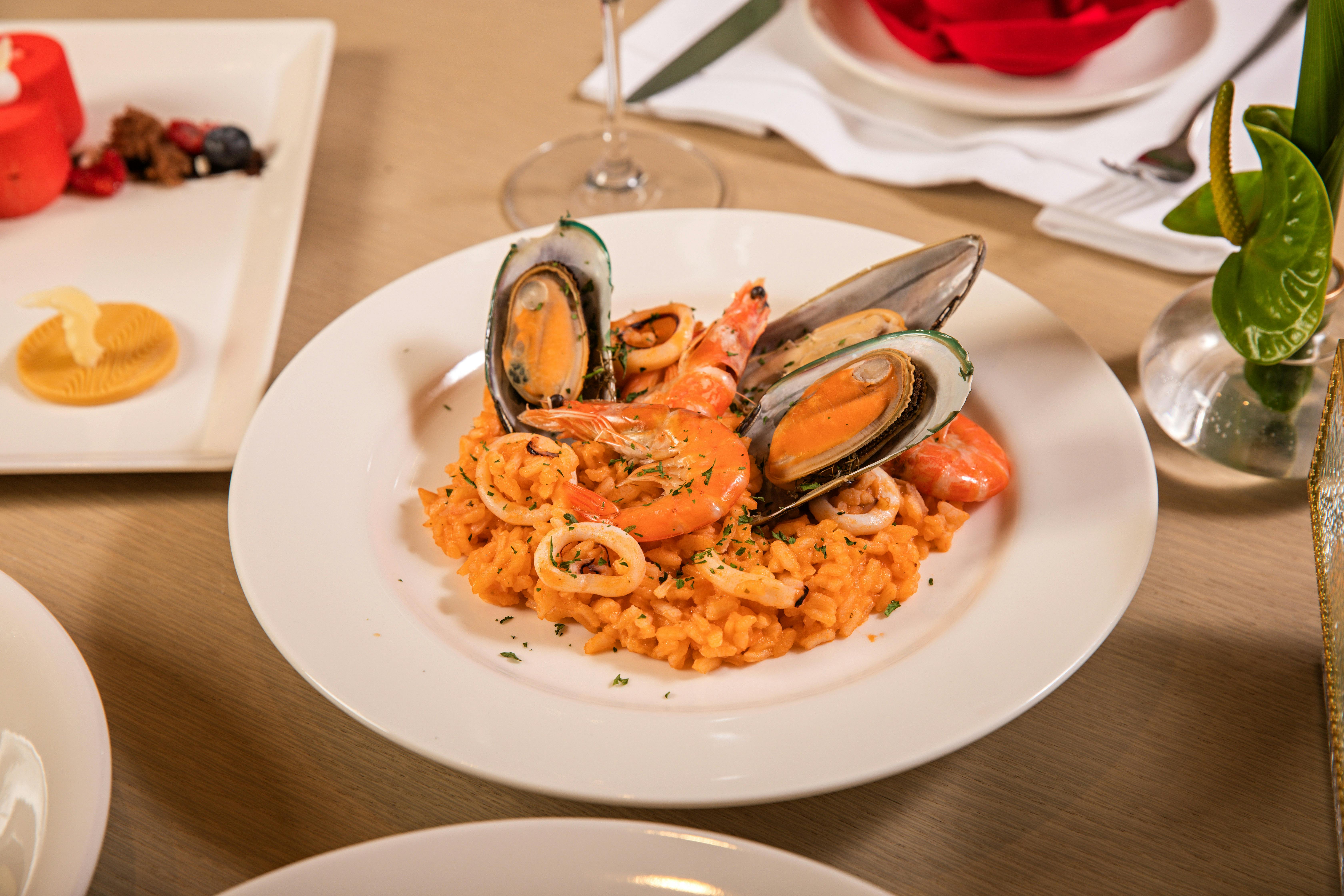 A vibrant seafood risotto dish featuring mussels and shrimp, elegantly presented on a fine dining ta