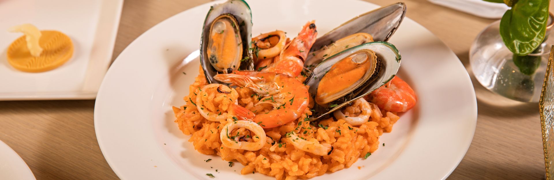 A vibrant seafood risotto dish featuring mussels and shrimp, elegantly presented on a fine dining ta