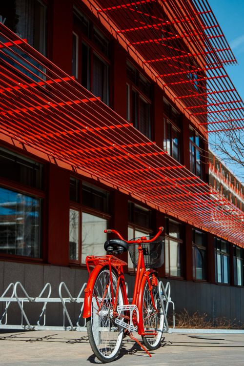Free Red bicycle parked against a modern architectural building with geometric patterns in Jönköping, Sweden. Stock Photo