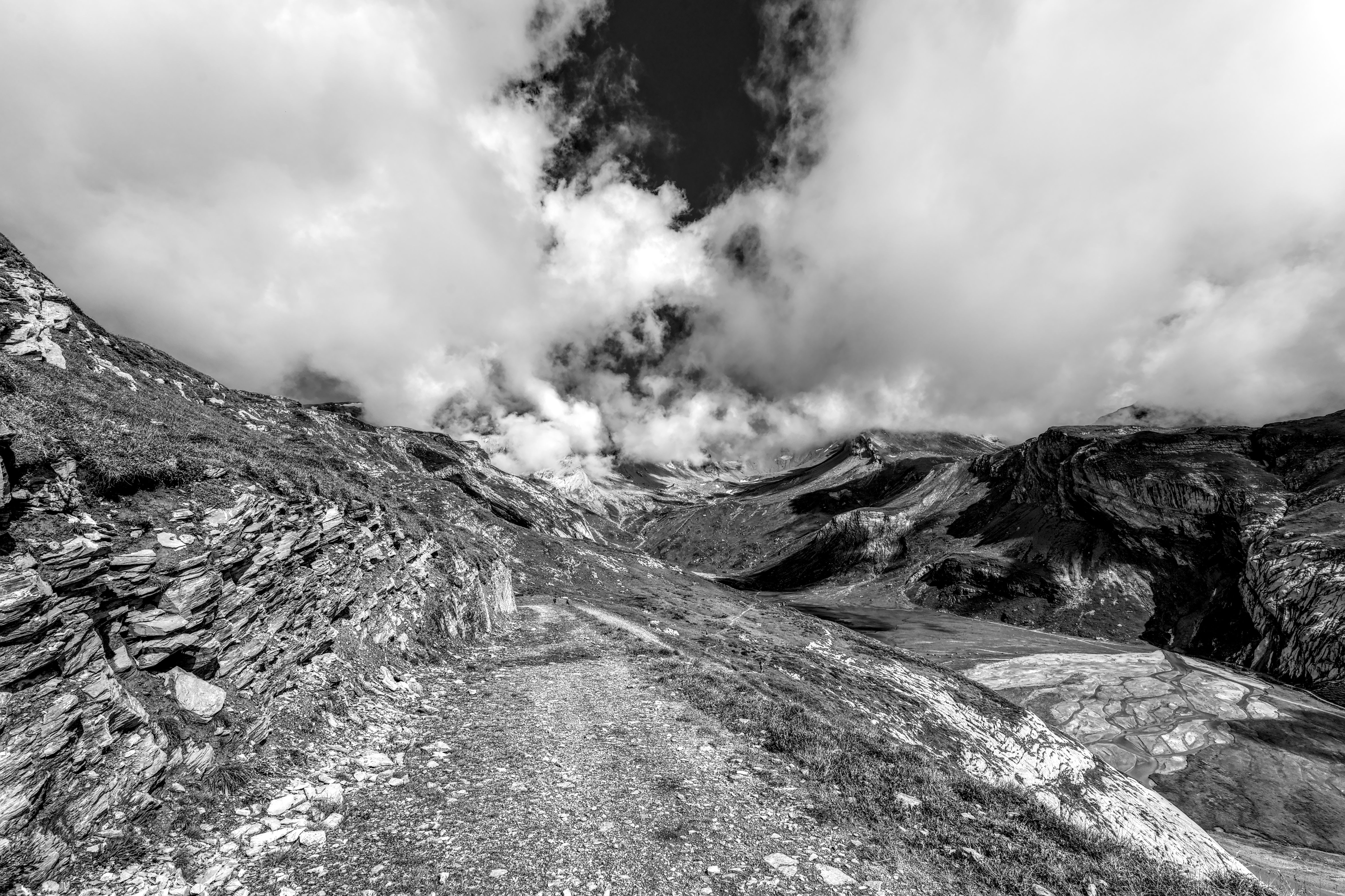 Dramatic black and white photo of the Swiss Alps with rugged mountains and clouded sky.