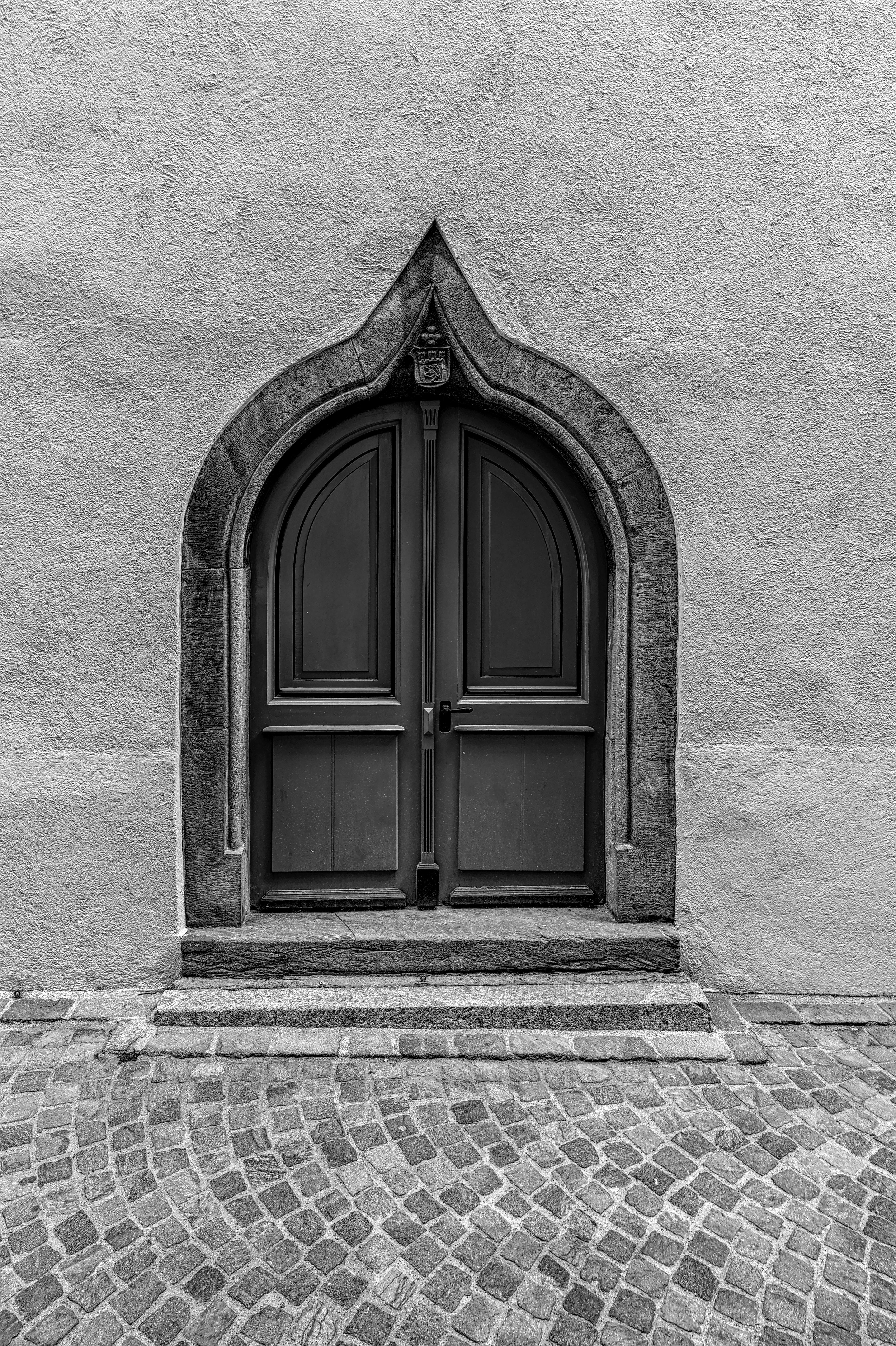 A captivating black and white photo of a Gothic arch doorway in Swiss architecture, exuding historical charm.