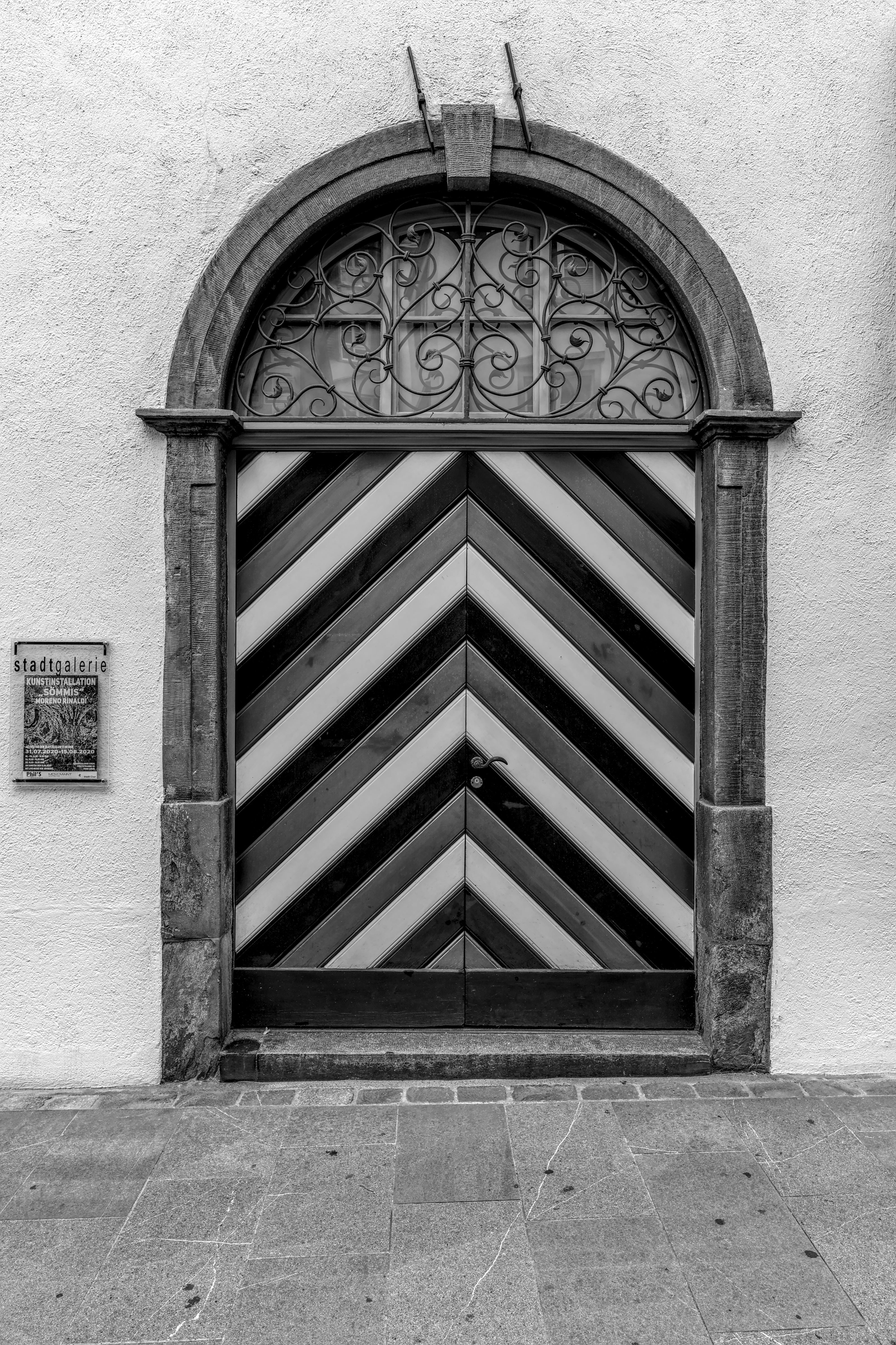 Black and white photo of an ornate vintage door in the Swiss Alps with striking chevron pattern.