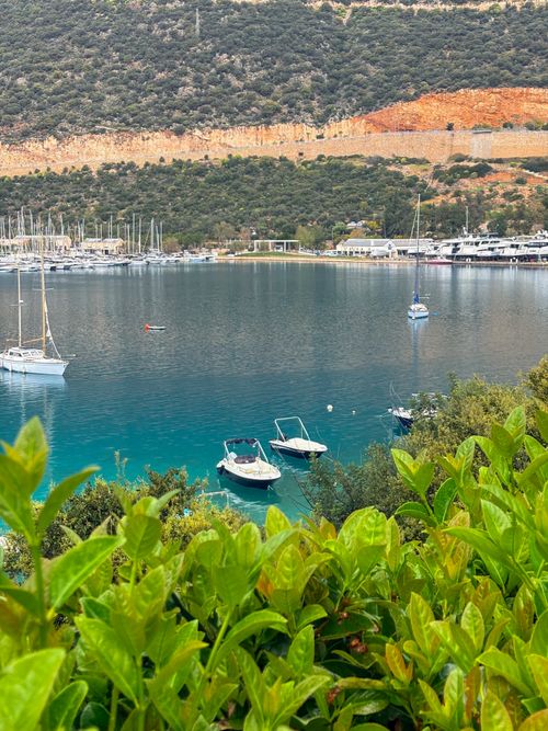 Free Tranquil harbor scene with yachts in Kaş, Antalya, surrounded by lush foliage and hills. Stock Photo