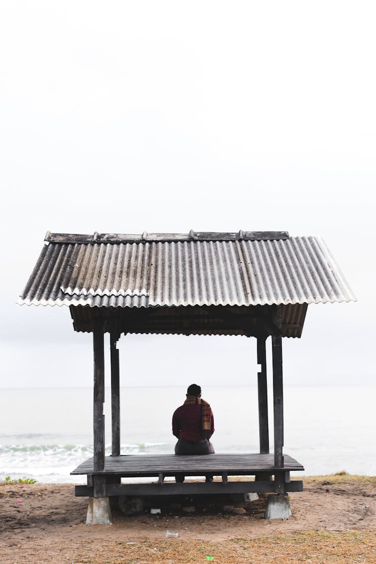 Man Sitting On A Wooden Shed