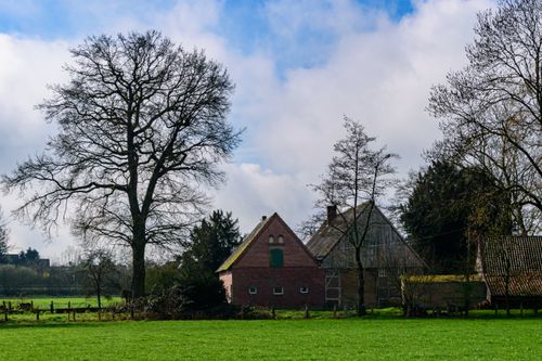 Free A picturesque rural farmhouse in Coesfeld, Germany, surrounded by lush greenery and clear skies. Stock Photo