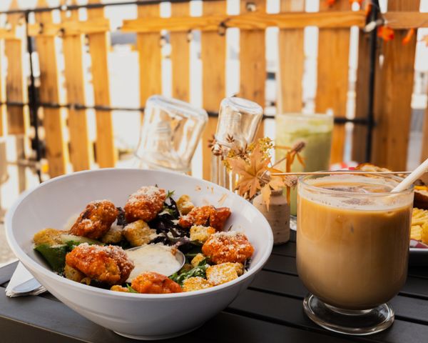 A crisp salad bowl beside an iced coffee on a sunny patio table — photo by Isa Noriega on Pexels