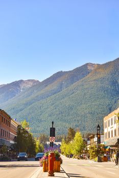Charming street view of a mountain town with scenic peaks in the background.