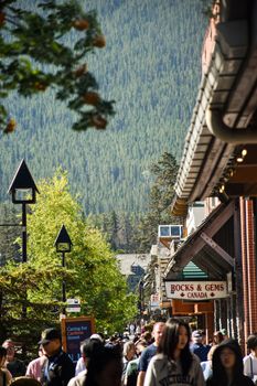 Crowded street in Banff, Canada, with shops and mountain backdrop.