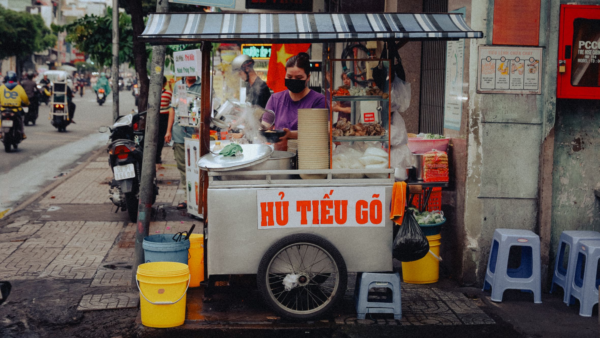Street food vendor serving hu tieu go noodles in bustling Ho Chi Minh City's outdoor market.