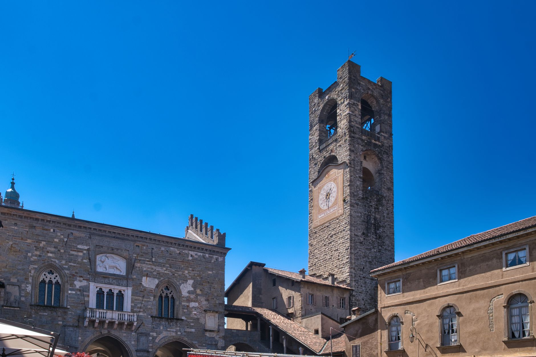 View of the historical Torre Civica and medieval architecture in Bergamo, Lombardy, under a clear bl