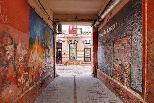 Colorful alleyway with vibrant graffiti leading to a historic building facade.
