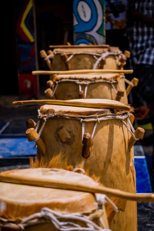 Free Row of traditional drums displayed outdoors in a vibrant market setting. Great for cultural or musical themes. Stock Photo