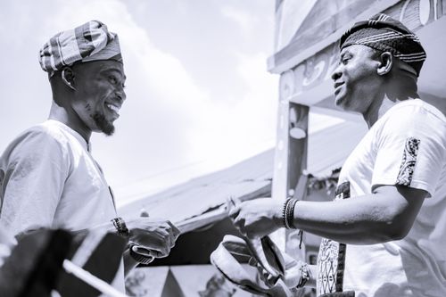 Free Two men in traditional African attire exchange a handshake at a vibrant outdoor market. Stock Photo