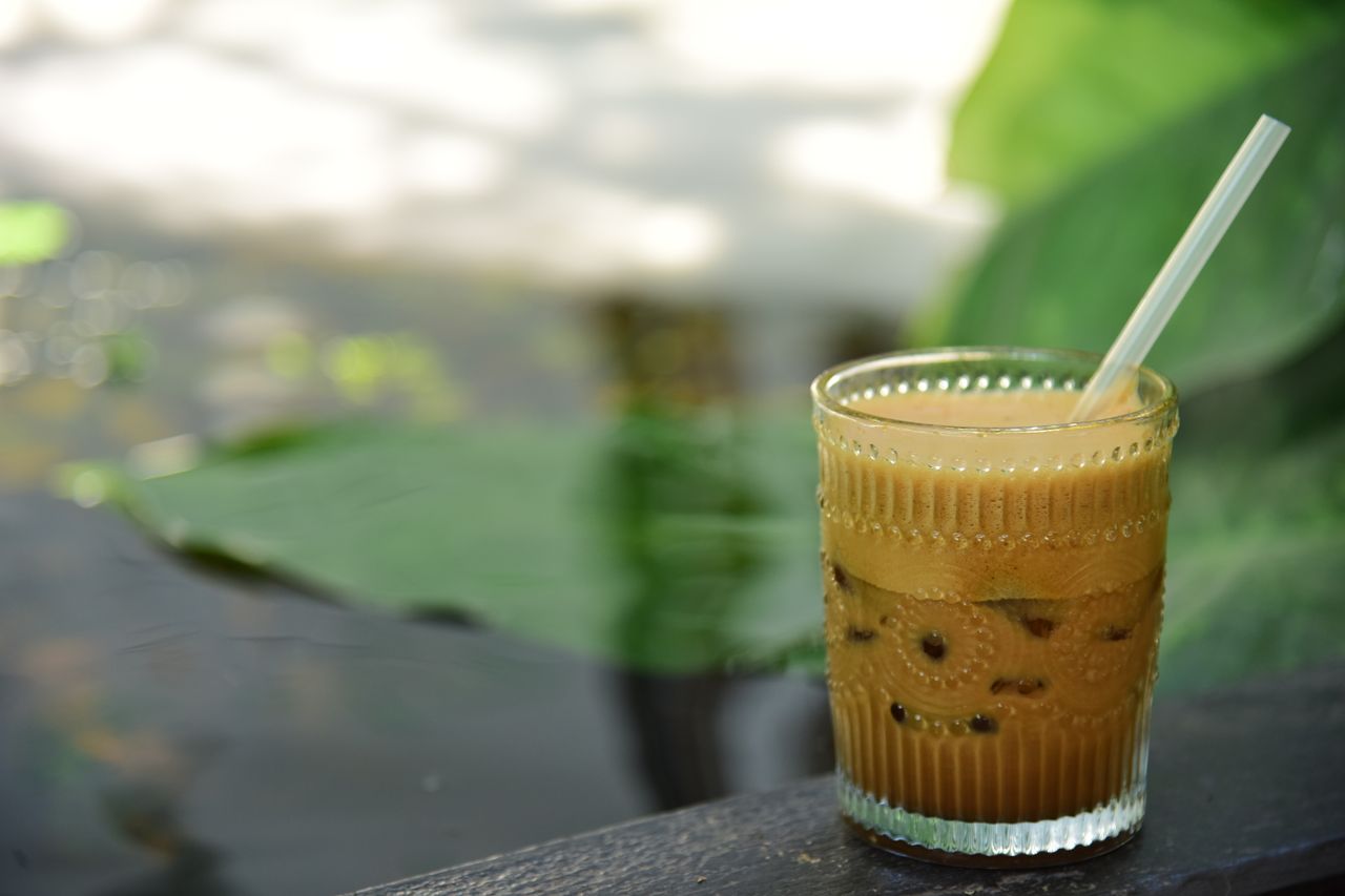refreshing iced coffee with a straw in a clear glass set against a sun