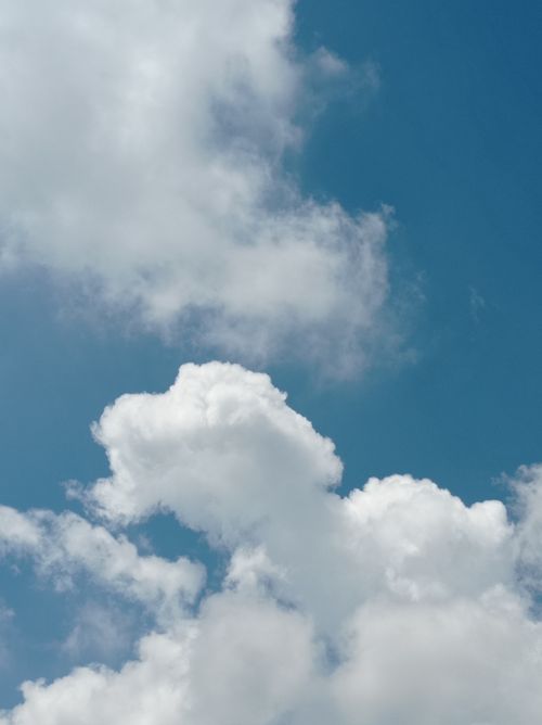 Free Fluffy cumulus clouds floating in a vibrant blue sky, perfect for serene and peaceful concepts. Stock Photo