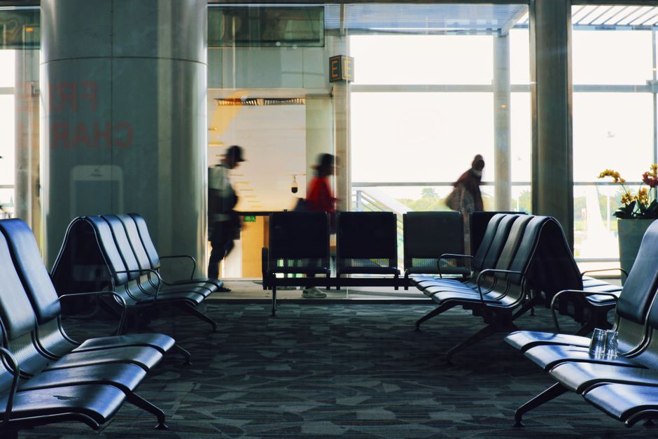 Indoor airport terminal with rows of seats and blurred moving people.