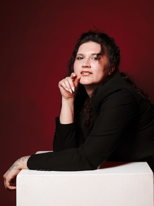 Free Stylish portrait of an adult person posed against a red backdrop, exuding confidence. Stock Photo