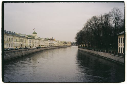 Free Quiet canal scene with historic buildings and bare trees lining the water. Stock Photo