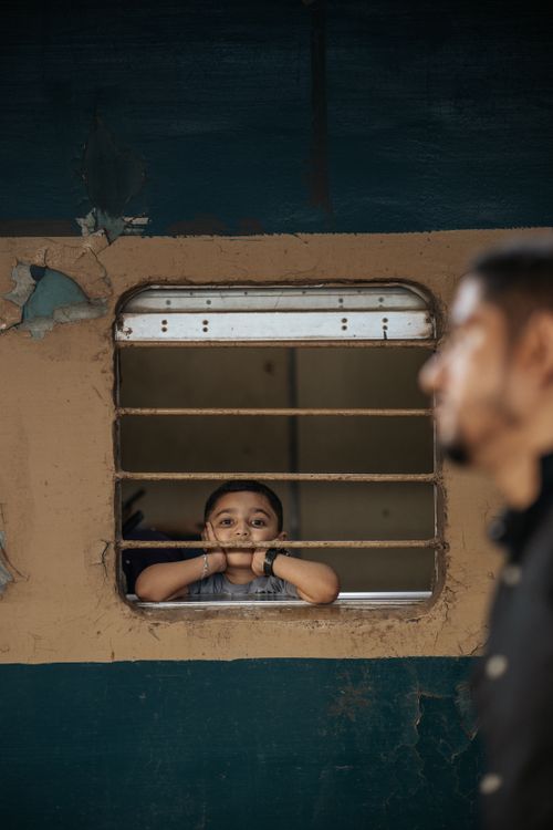 Free A young boy gazes out from a train window in Chattogram, Bangladesh, capturing a moment of curiosity and travel. Stock Photo