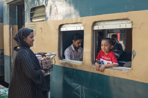 Free A street vendor interacts with a child looking out from a train at Chattogram station. Stock Photo