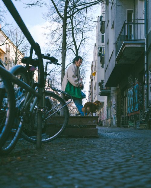 Free Man walking dog on a graffiti-lined street in Berlin, highlighting urban life. Stock Photo
