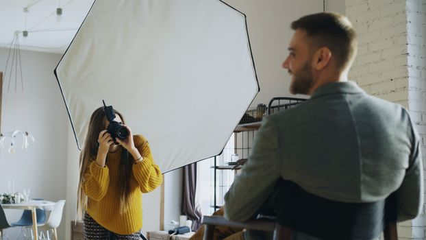 A professional photographer captures a portrait indoors using softbox lighting for a client photoshoot.