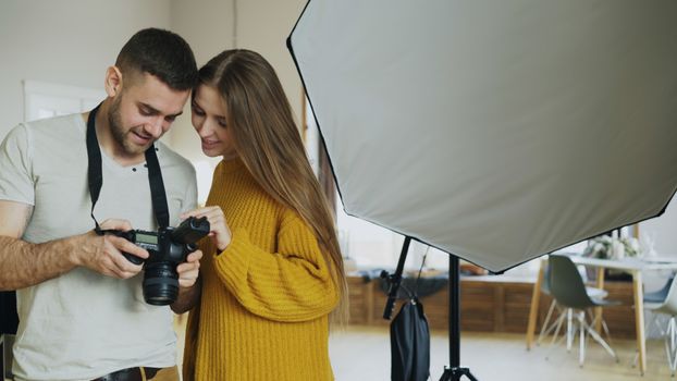 Photographer shares camera screen with model indoors in a photography studio.