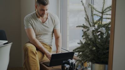Man working on a laptop beside a window — photo by Vitaly Gariev on Pexels