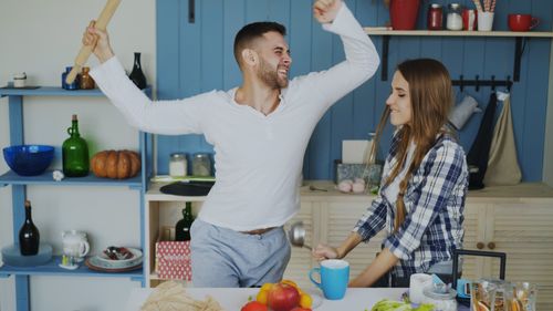 Free A joyful couple having fun while preparing food in a cozy kitchen setting. Stock Photo