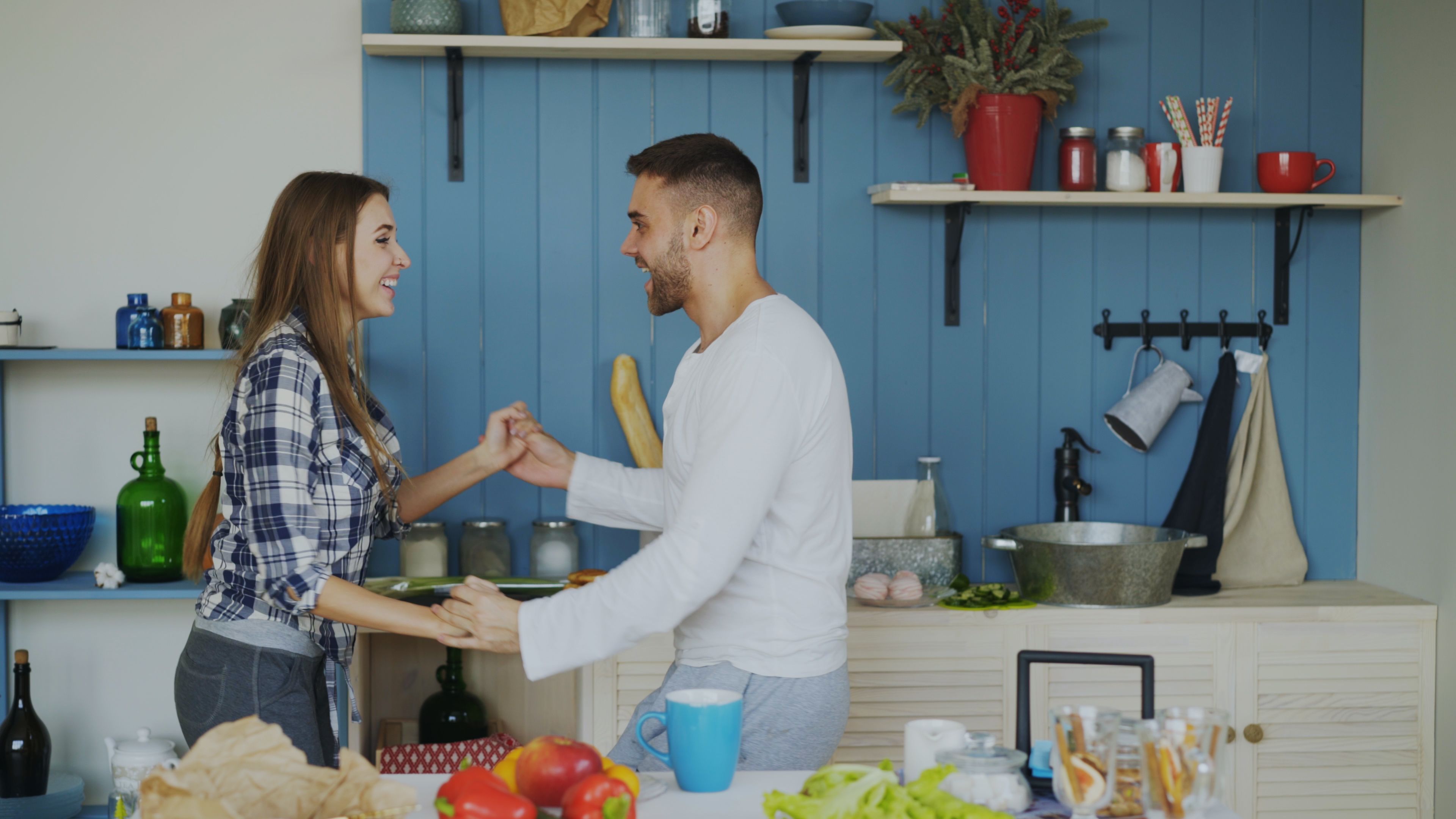 Happy couple dancing and laughing together in a modern kitchen setting.