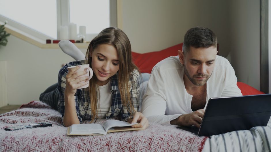 Couple using a laptop to book their next affordable island trip - cheap island getaways for couples Couple using a laptop to book their next affordable island trip - cheap island getaways for couples