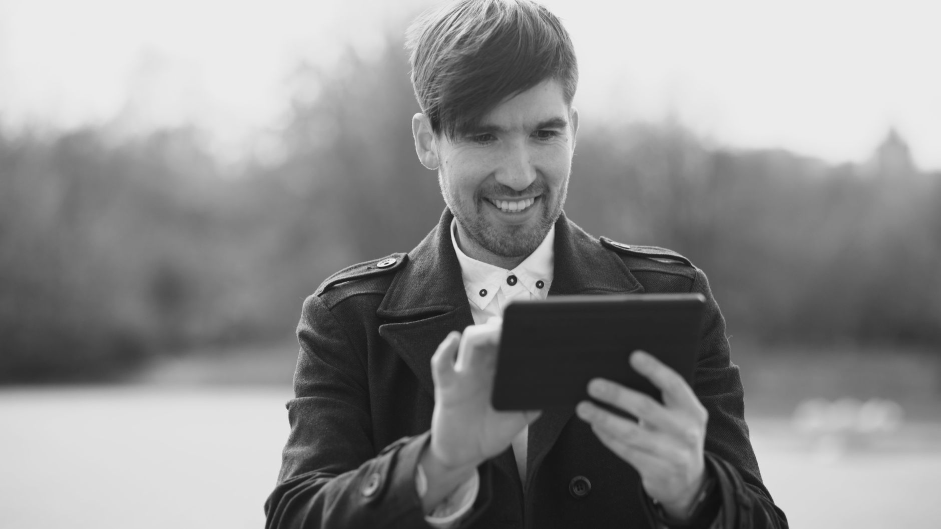 Happy man with a tablet in an outdoor setting, black and white style.