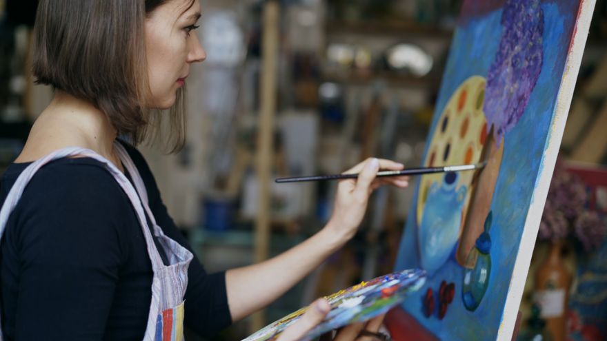 A focused artist painting a vibrant canvas in a studio, representing the work of consciously developing and expressing a natural talent