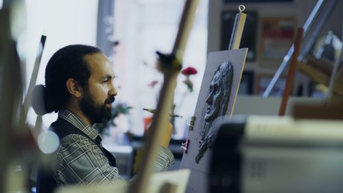 Free A male artist focused on creating a portrait in his art studio. Stock Photo