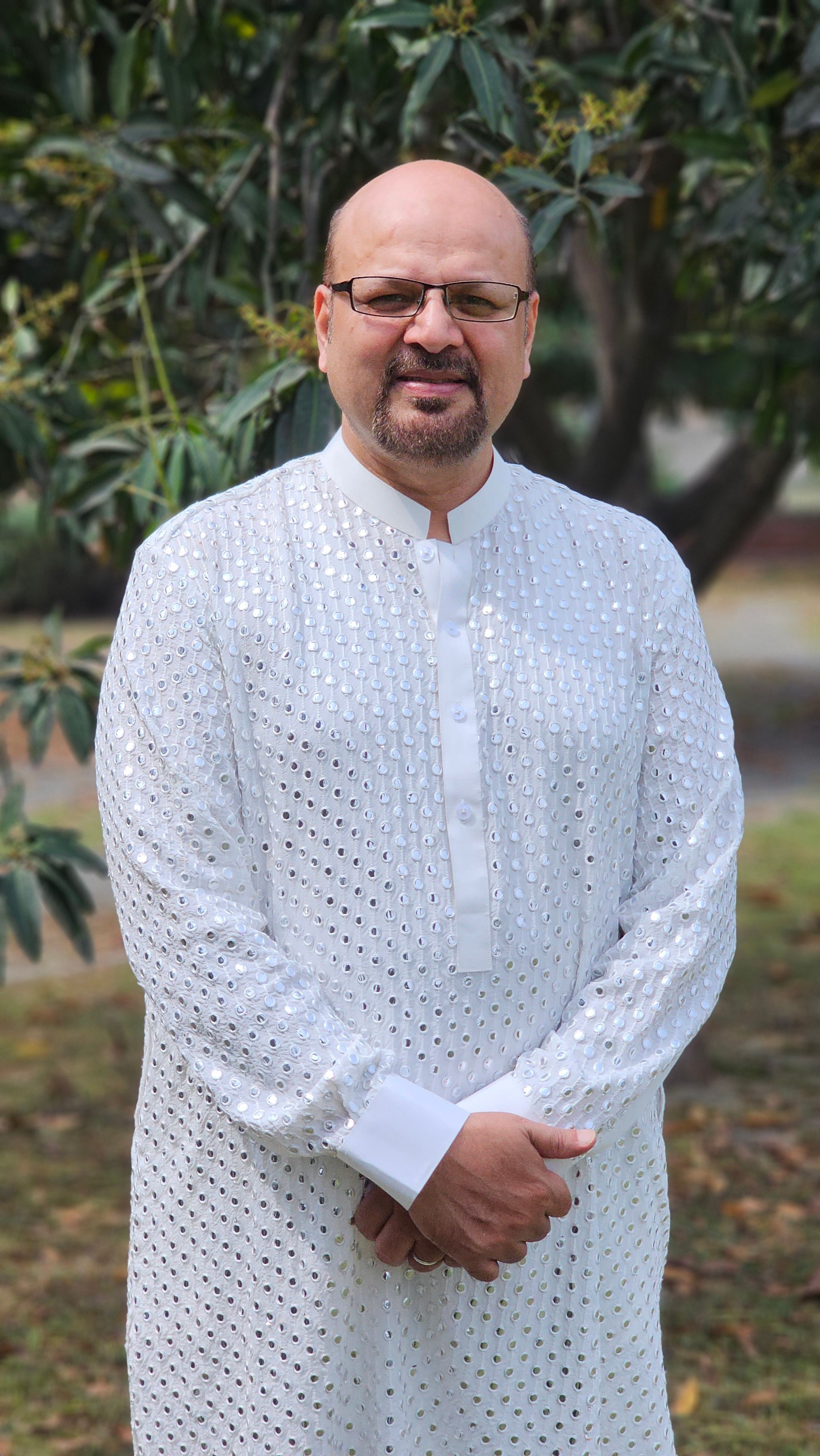 Portrait of a man wearing traditional white attire in an outdoor setting.