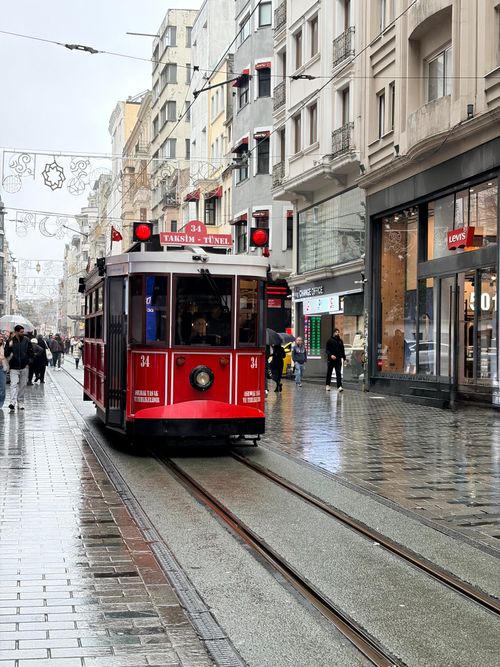 Free Classic red tram on a rainy day traversing İstiklal Street in vibrant Istanbul, Türkiye. Stock Photo
