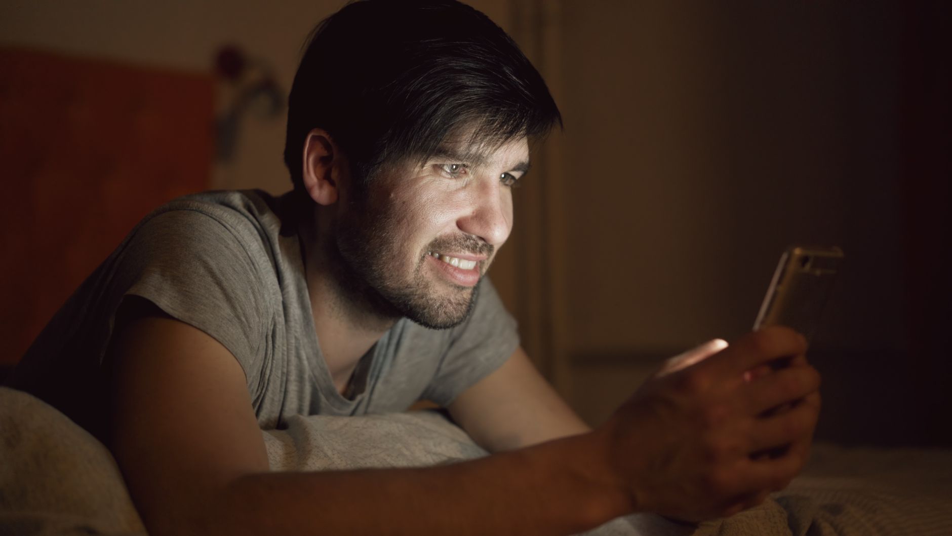 Man checking a face-rating app on his phone late at night