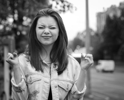 Black and white portrait of a young woman outdoors, expressing playful determination with a street background.