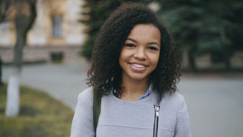 Free Young woman smiling in an outdoor setting, wearing casual attire. Stock Photo