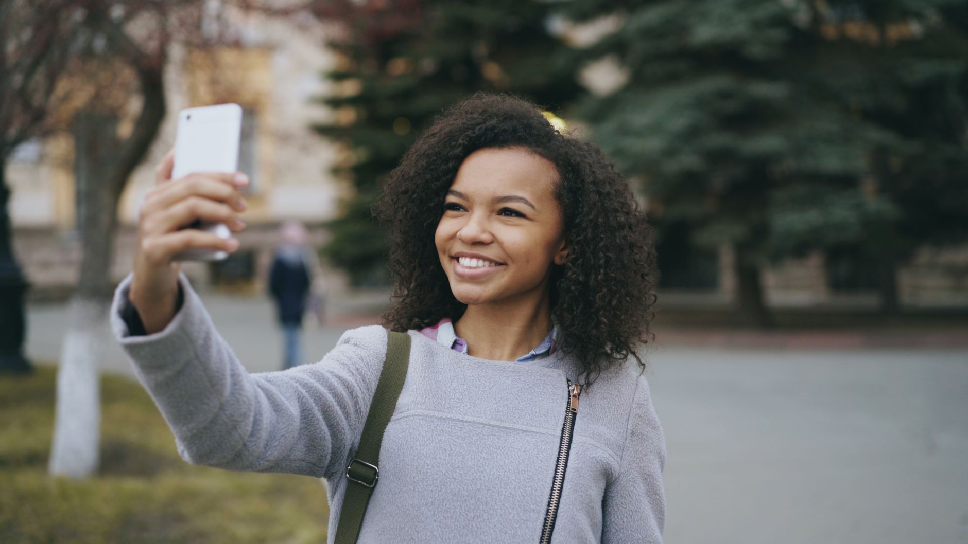 Smiling young woman takes a selfie in an outdoor setting. Capturing a joyful moment.