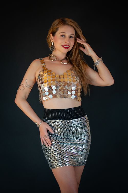 Free Portrait of a stylish woman in a shimmering gold sequin outfit against a dark background. Stock Photo
