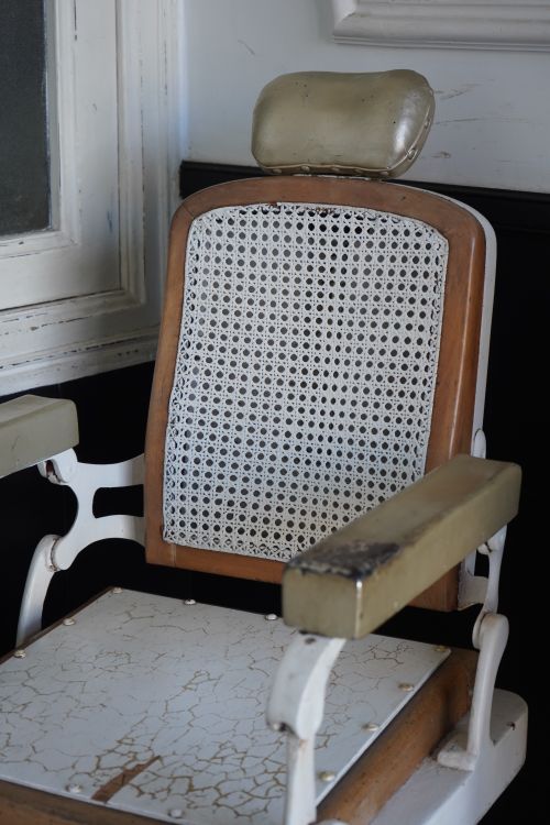 Free Close-up of a vintage barbershop chair with a textured seat and armrest in a rustic setting. Stock Photo