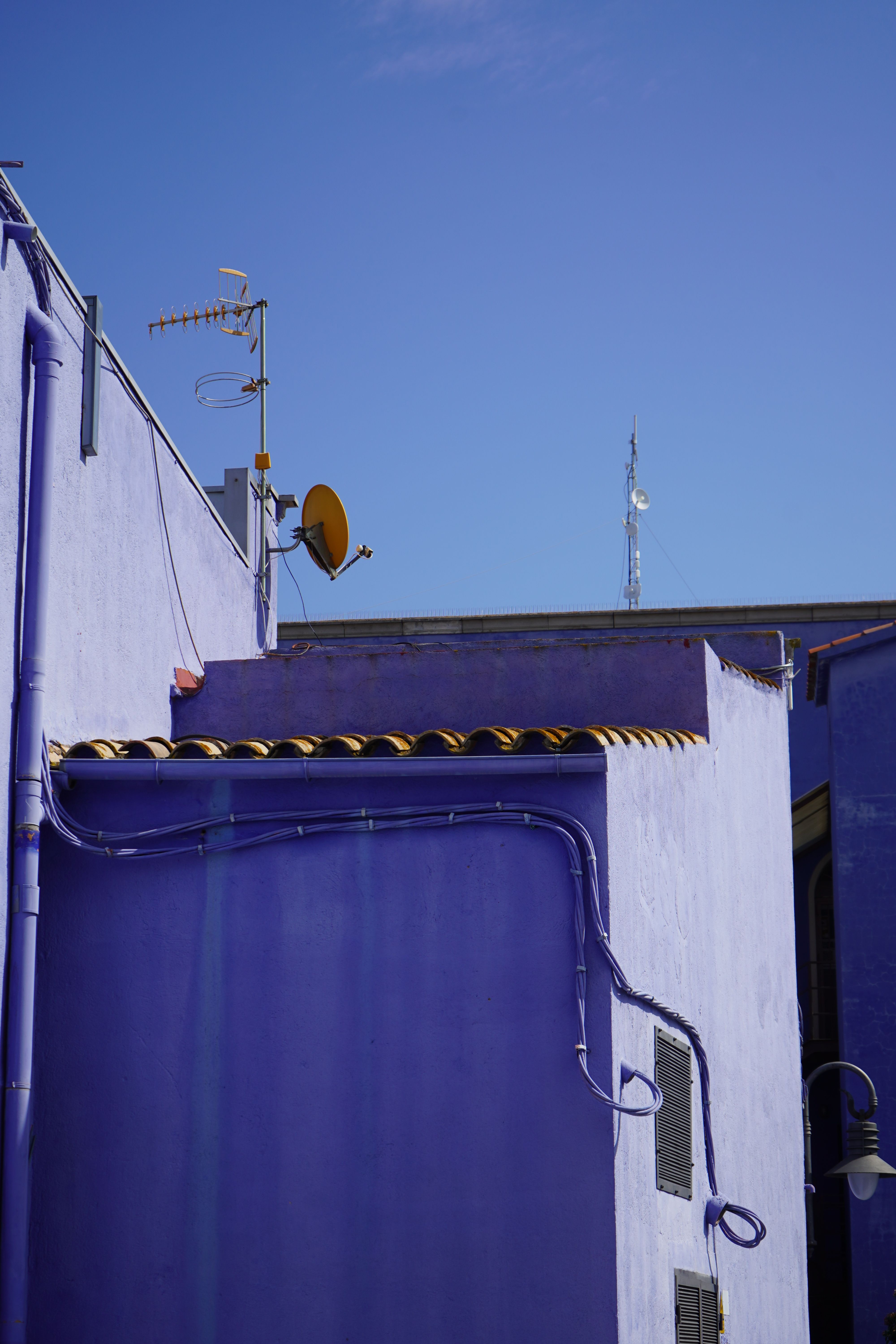 Purple buildings with antenna under clear blue sky, creating a vibrant urban scene.