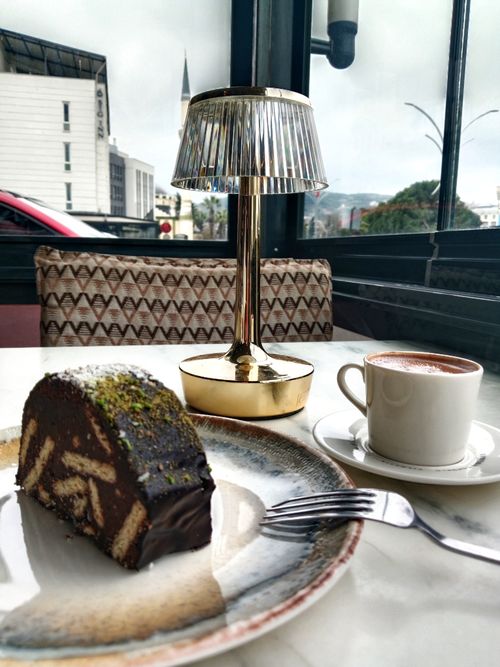 Free A cozy cafe setting featuring a delicious chocolate dessert, a cup of coffee, and a stylish lamp on a rainy day. Stock Photo