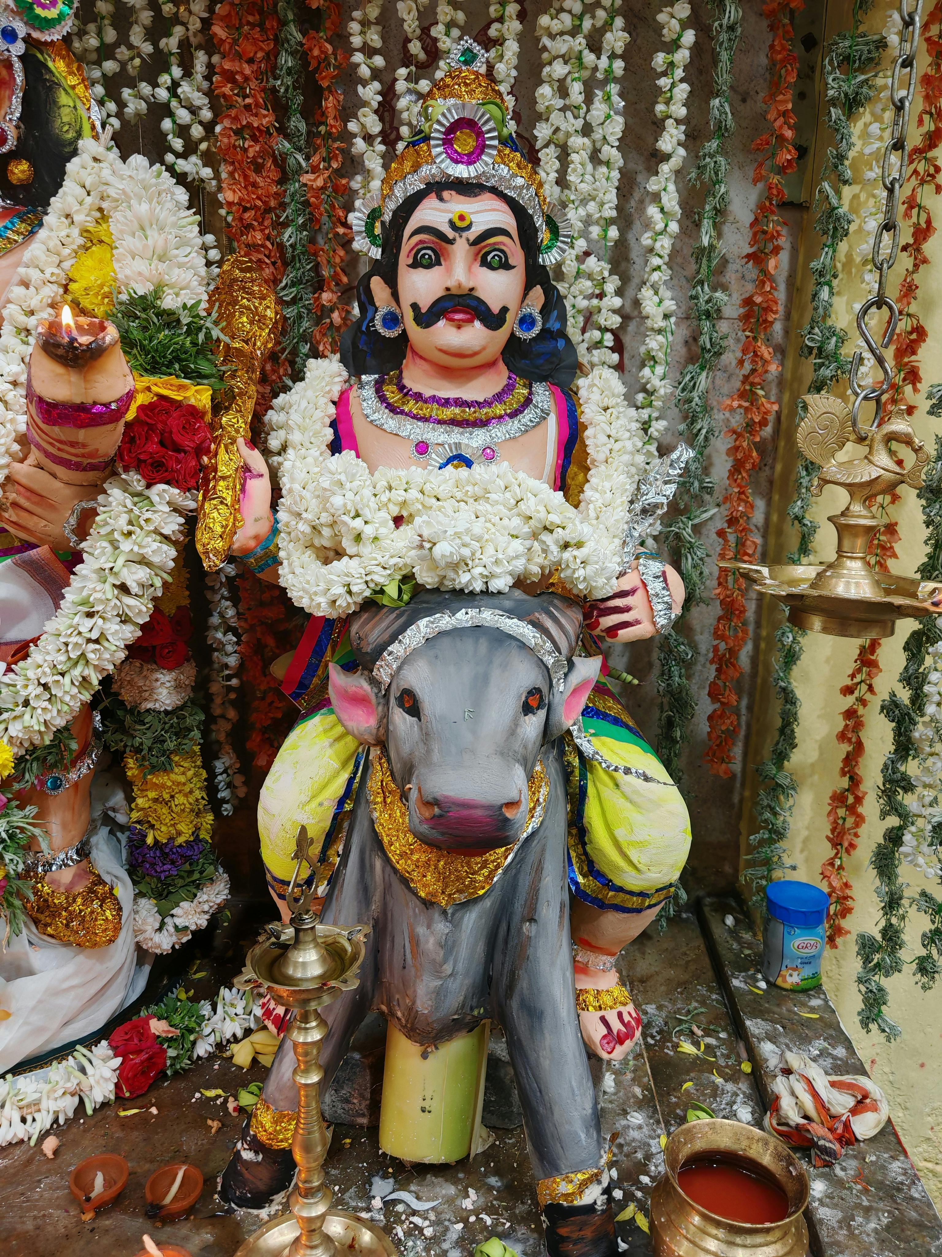 Colorful statue of Hindu deity adorned with garlands at a temple in Sivakasi, India.