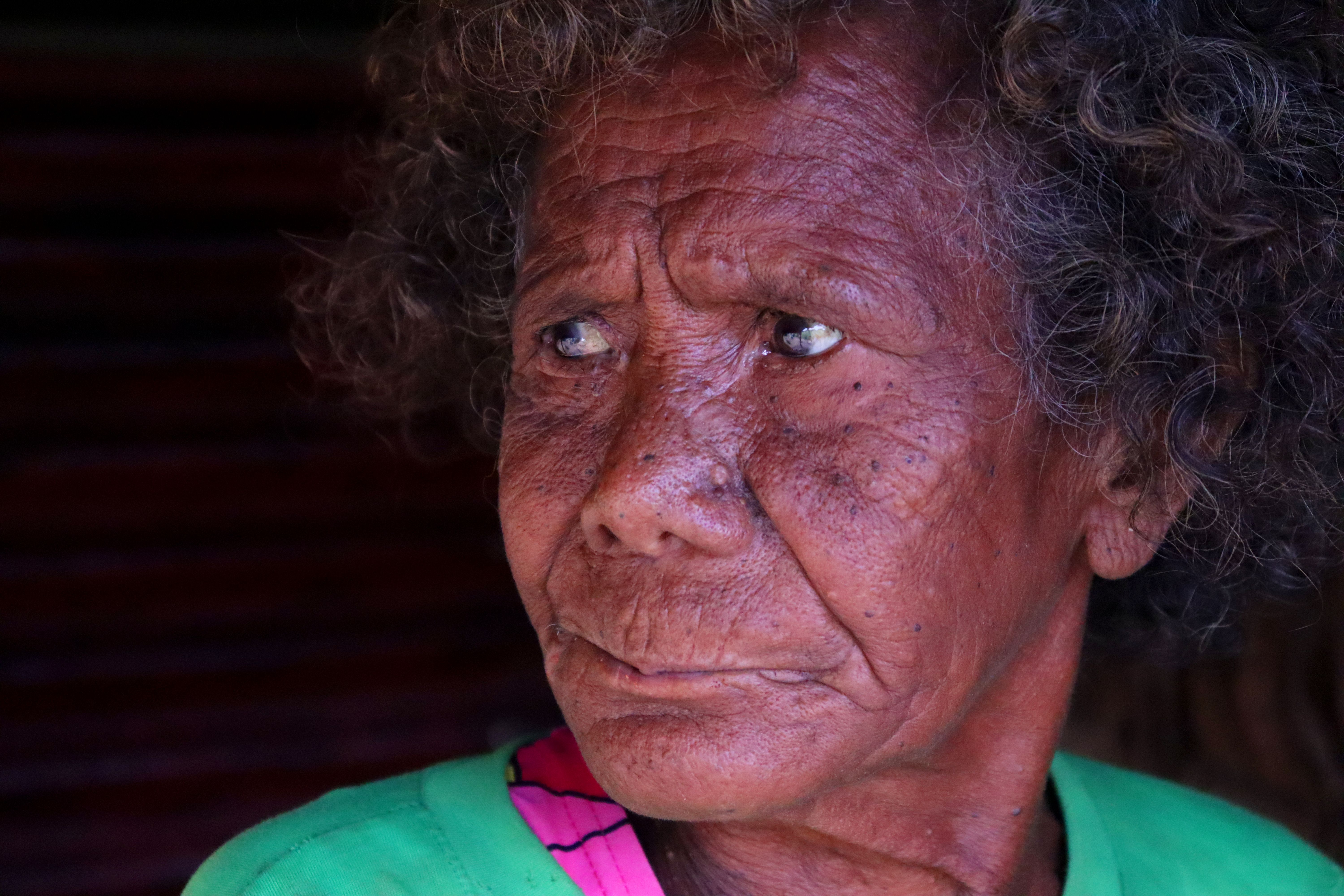 Close-up portrait of an elderly person with expressive eyes in natural lighting.