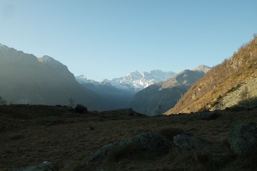Breathtaking view of snow-capped mountains in an Italian valley under a clear sky.