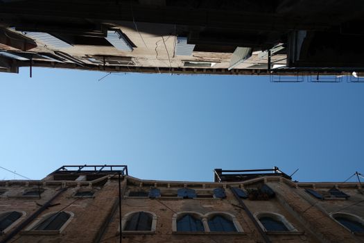 View from below of two historic buildings with blue sky in Venice, Italy.