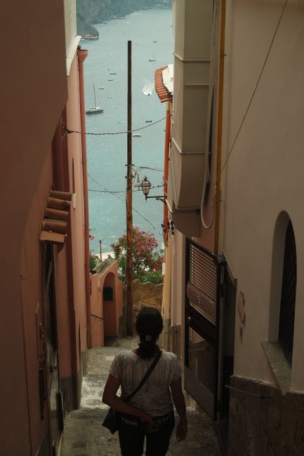 A narrow street in Sorrento, Italy, leading to a stunning view of the bay, framed by pastel buildings.