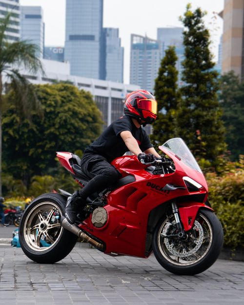 Free A motorcyclist rides a red Ducati through a city landscape. Modern urban vibe. Stock Photo